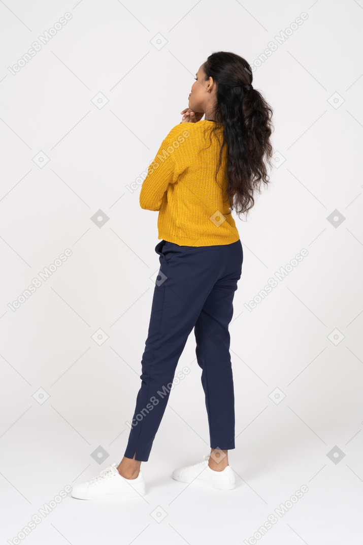 Vista lateral de uma garota pensativa em roupas casuais tocando o queixo com os dedos