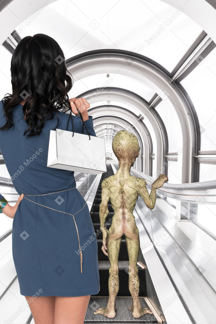 Woman in blue dress standing next to an alien on escalator