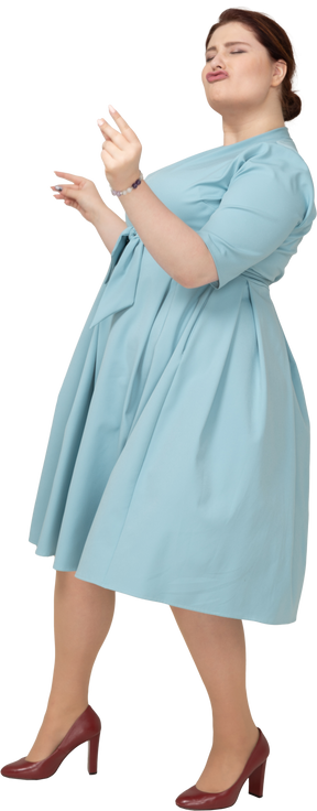 Vue latérale d'une femme en robe bleue dansant