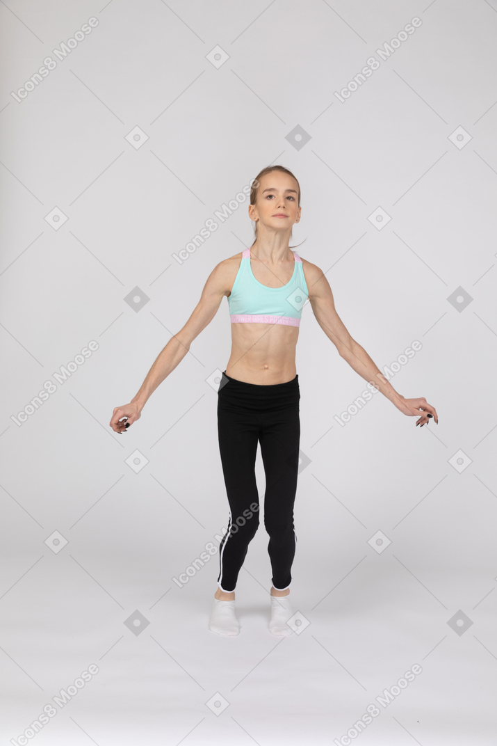 Seitenansicht eines jugendlich mädchens in der sportbekleidung, die hockt und hände auf hüften setzt