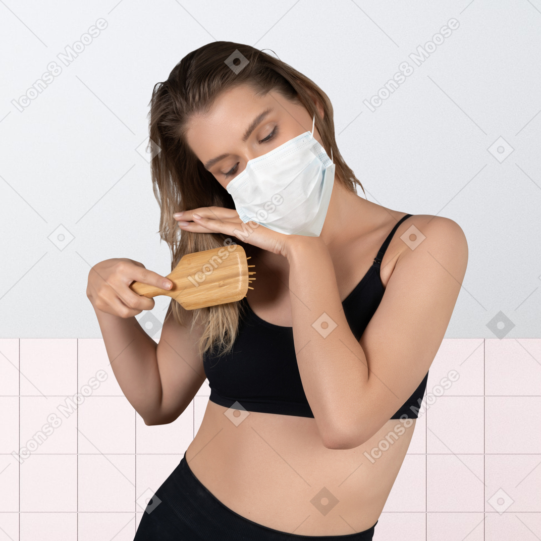 A woman with a face mask is brushing her hair