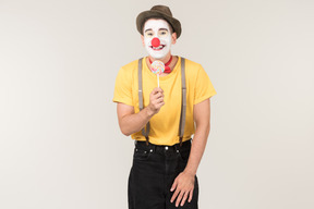 Smiling male clown holding lollipop