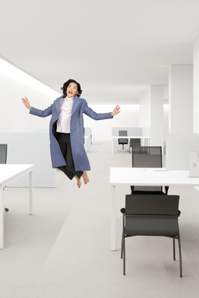 A woman is jumping in an empty office