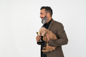 Homem bonito com um cachorrinho em pé no perfil e segurando um copo de vinho