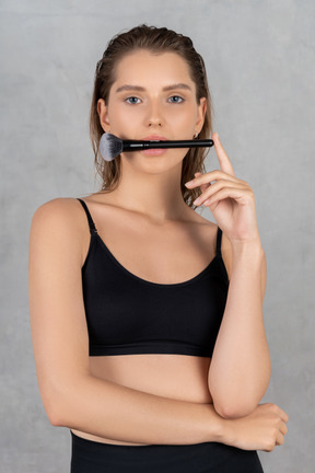 Beautiful woman holding makeup brush in her mouth