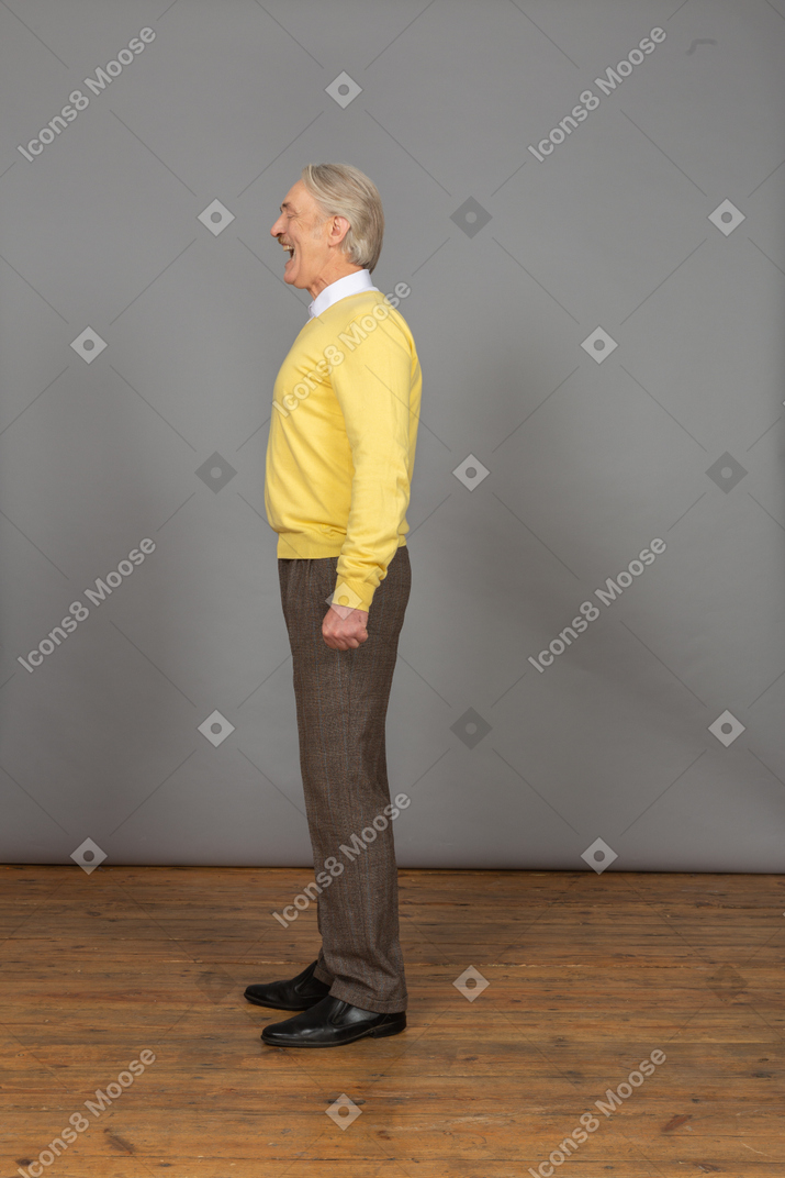 一个微笑的人，在一件黄色的套衫，张着嘴，闭着眼睛的侧视图