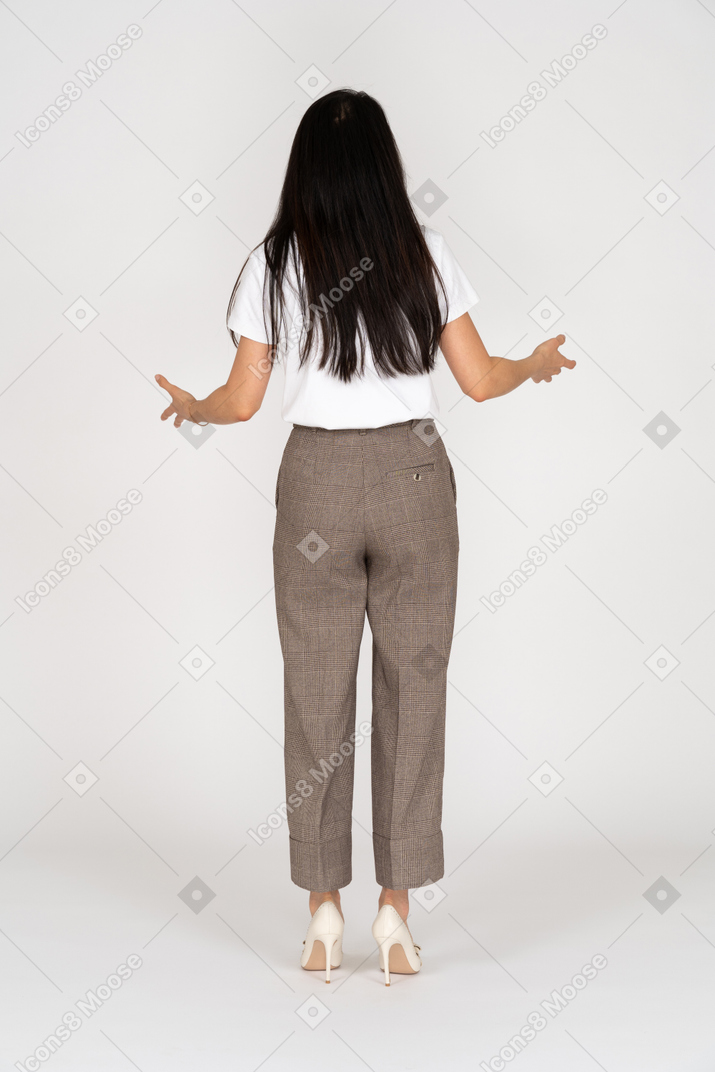 Back view of a complaining young lady in breeches and t-shirt outspreading her hands