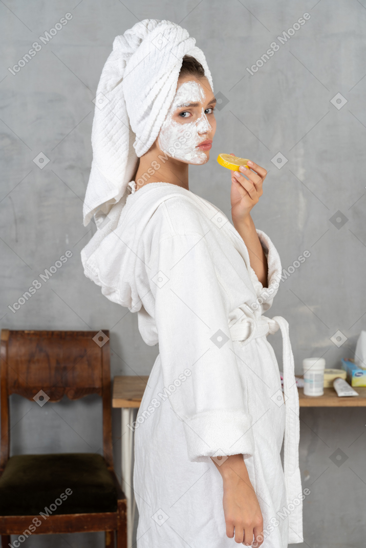 Side view of a woman in bathrobe holding a lemon