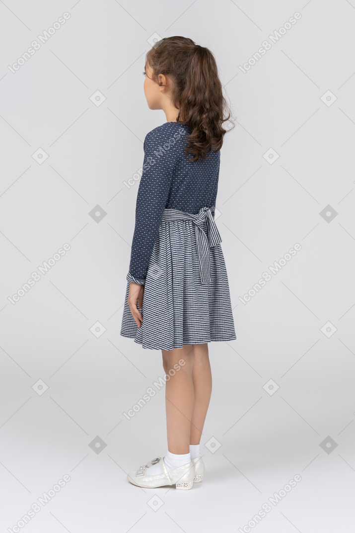 Back view of a girl with a ponytail standing with arms at sides