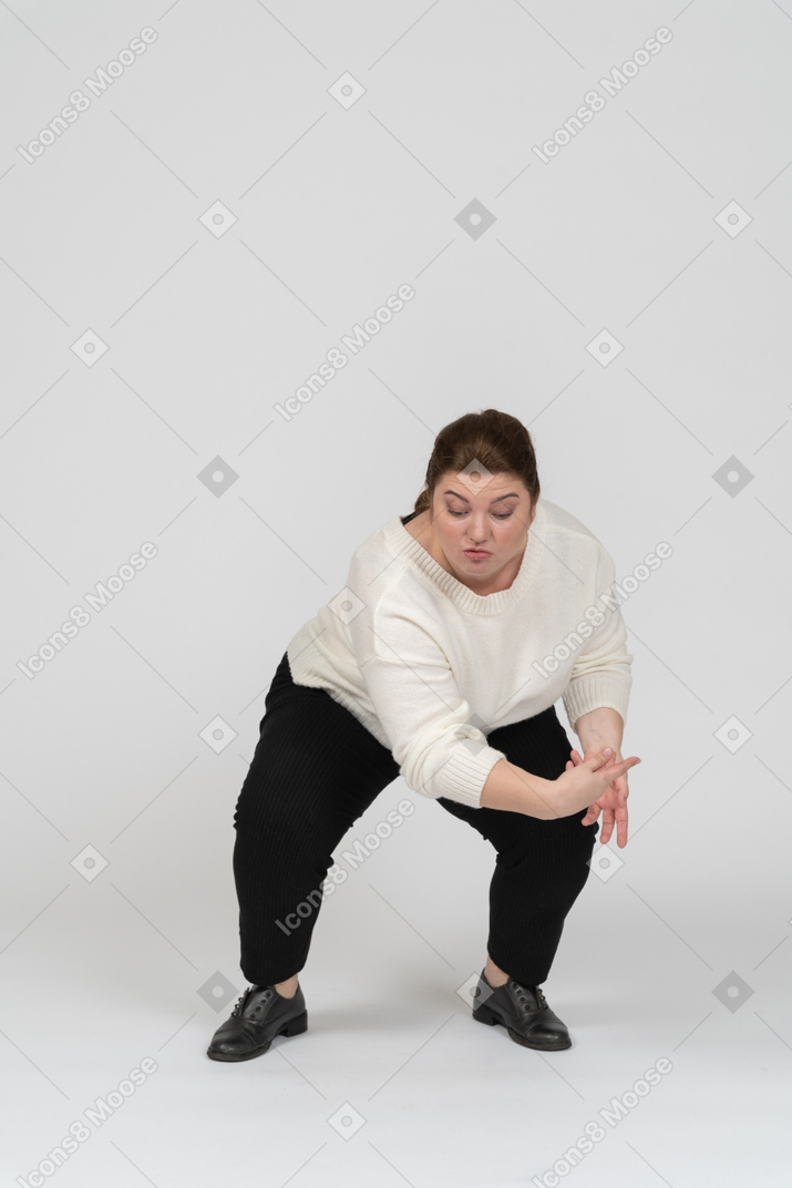 Vista frontal de uma mulher gorducha em roupas casuais agachada
