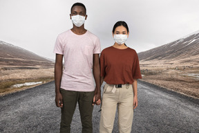 A man and a woman wearing masks standing on a road