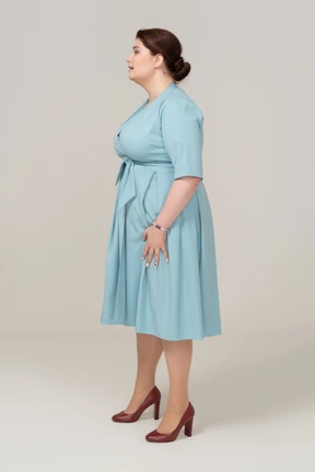 Woman in blue dress standing in profile