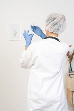 Back view of a young female doctor holding a syringe