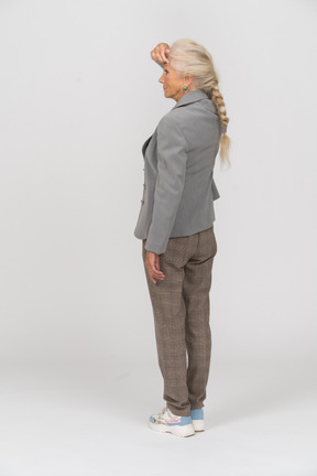 Rear view of an old woman in suit touching forehead