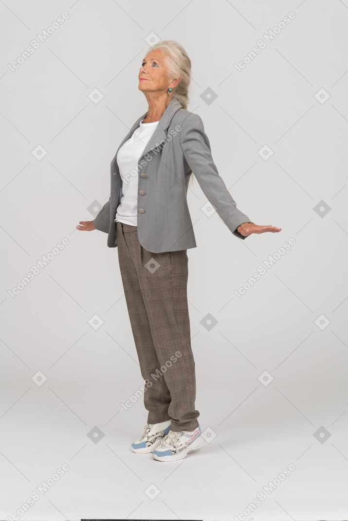 一位身着西装的老太太站在脚趾上，伸出双臂的侧视图