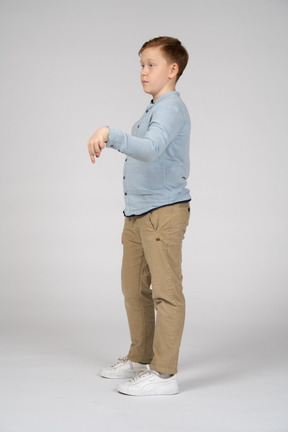Vista lateral de um menino apontando para baixo com o dedo
