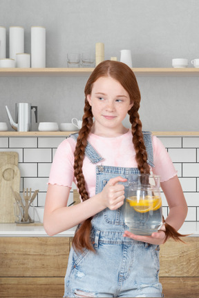 A young girl holding a pitcher of orange water