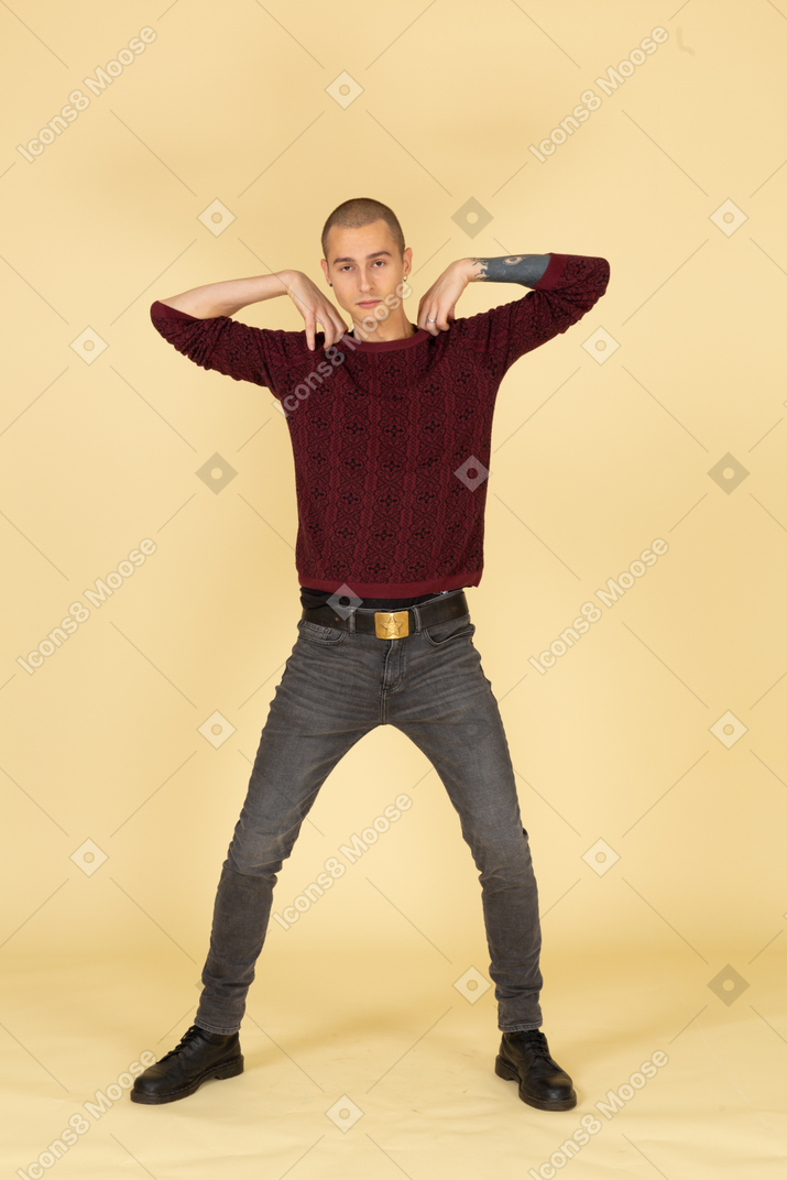 Вид спереди молодого человека в красном пуловере, касающегося плеч