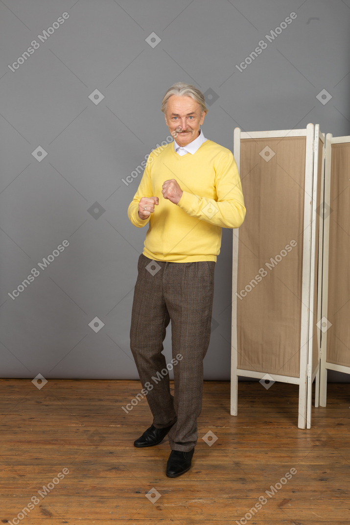 Vista frontal de un anciano sonriente apretando los puños