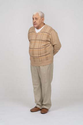 Vista frontale di un vecchio in abiti casual in piedi con le mani dietro la schiena