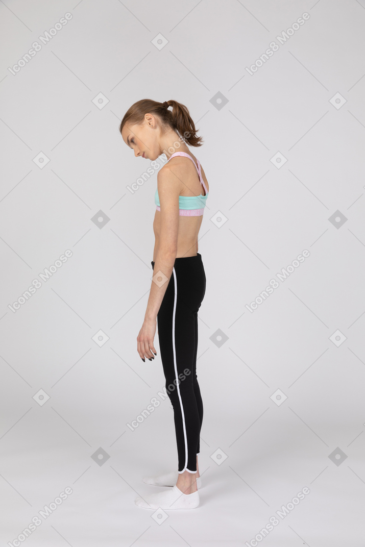 Vista lateral de una jovencita en ropa deportiva mirando hacia abajo