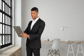 A man in a suit is using a tablet computer in an office