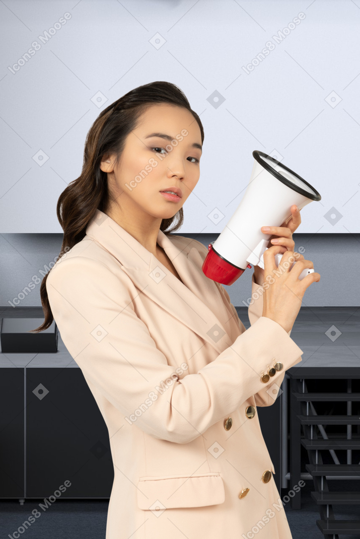 A woman in a suit holding a red and white megaphone
