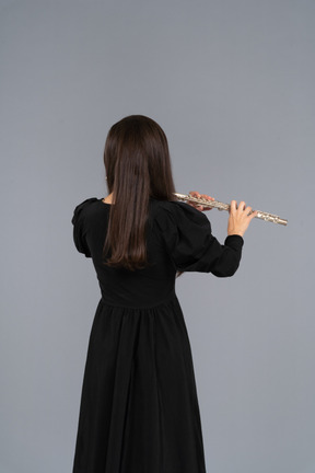 Black view of a young lady in black dress playing the flute