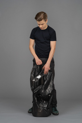 A young man filling a trash bag