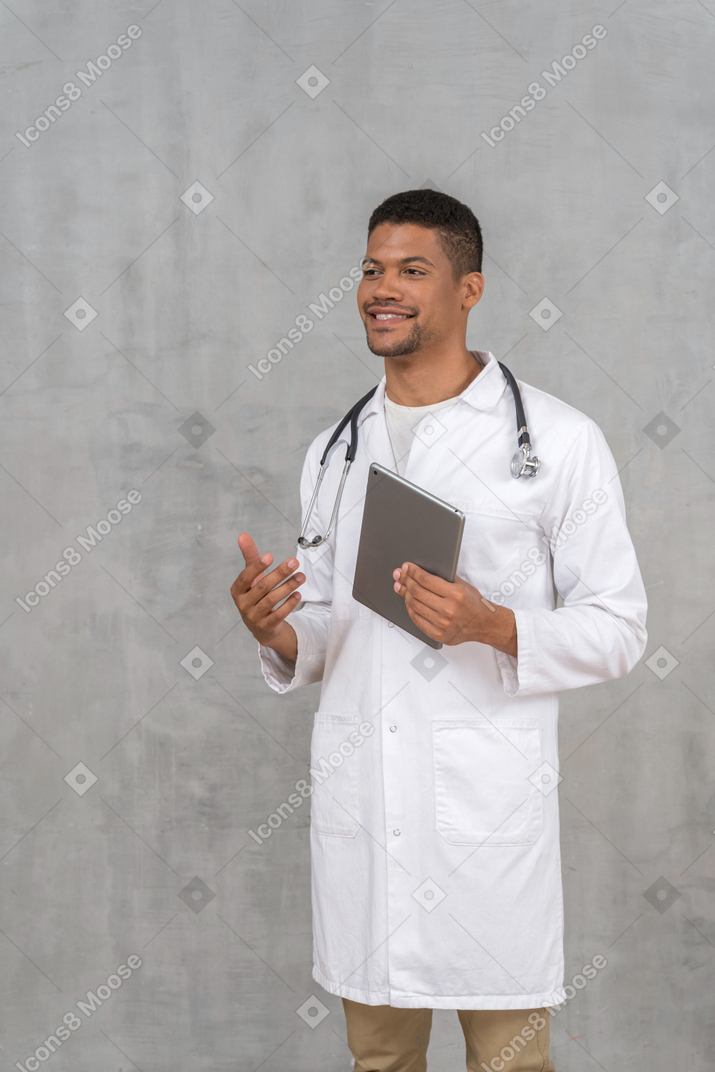 Doctor sonriente con tableta hablando con alguien