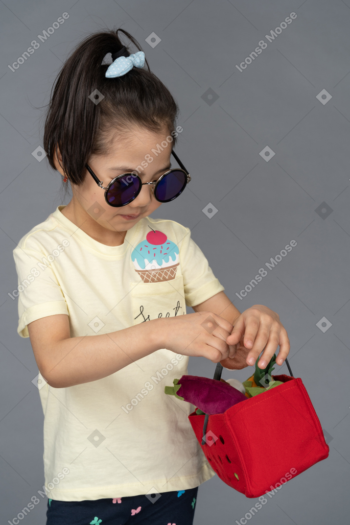 쇼핑 바구니를 들고 선글라스에 어린 소녀의 근접