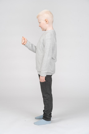 Side view of a little boy standing with his fist raised