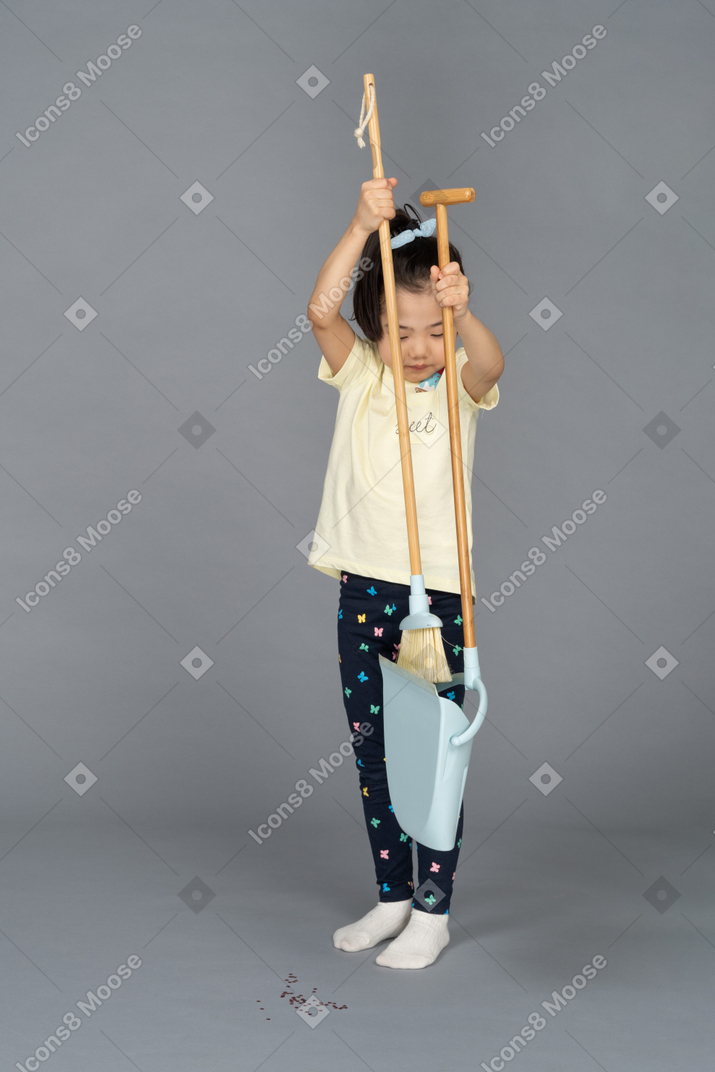 Front view of a little girl putting away the broom
