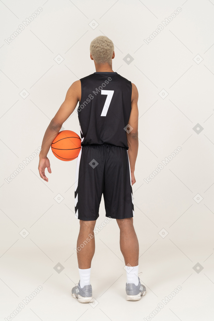 Vista posteriore di un giovane giocatore di basket maschile che tiene una palla
