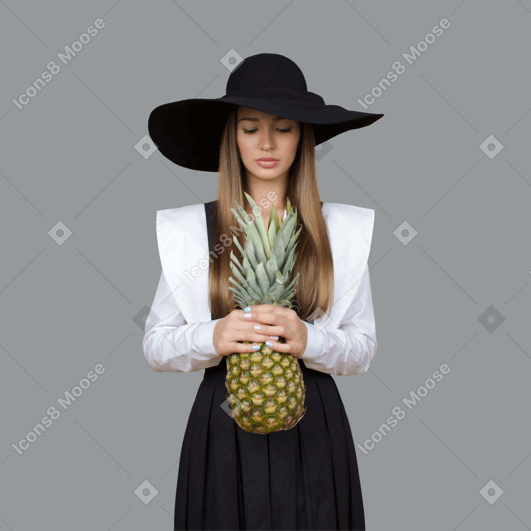 パイナップルを保持している帽子の女性