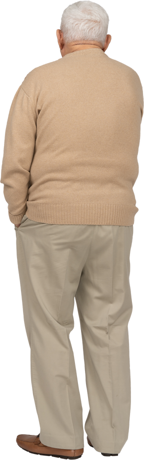 Vista trasera de un anciano con ropa informal de pie con la mano en el bolsillo