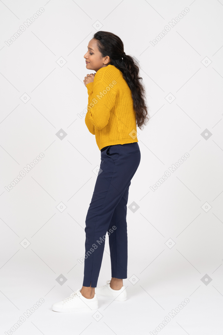 Side view of a cute girl in casual clothes making praying gesture