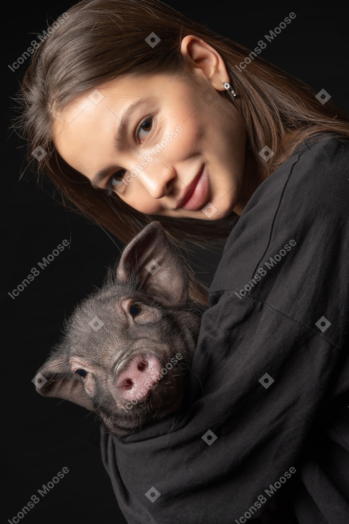 Menina bonita, segurando o porco em miniatura