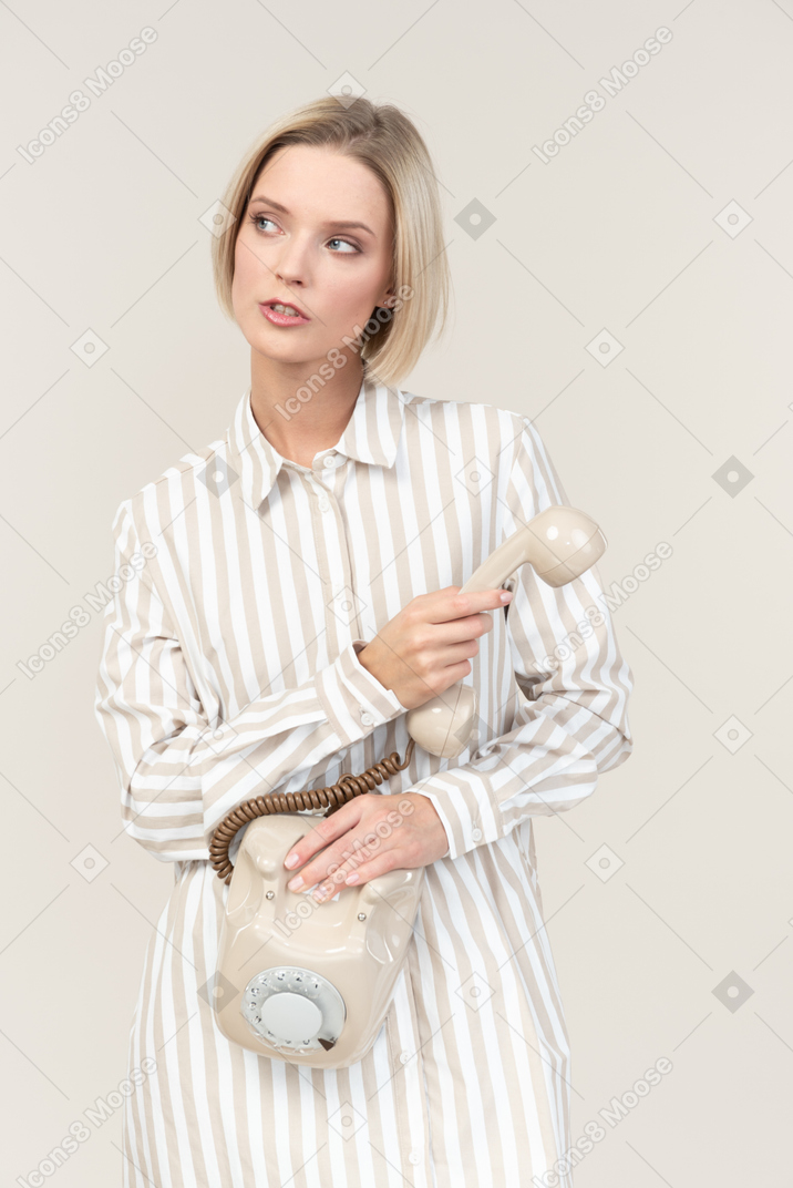 Dreamy young woman holding old rotary phone