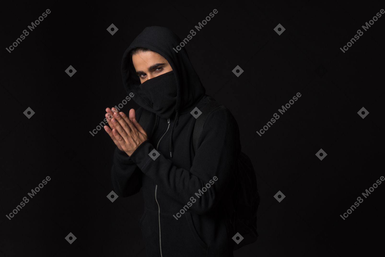 Hacker guy with covered face standing in the dark with hands folded