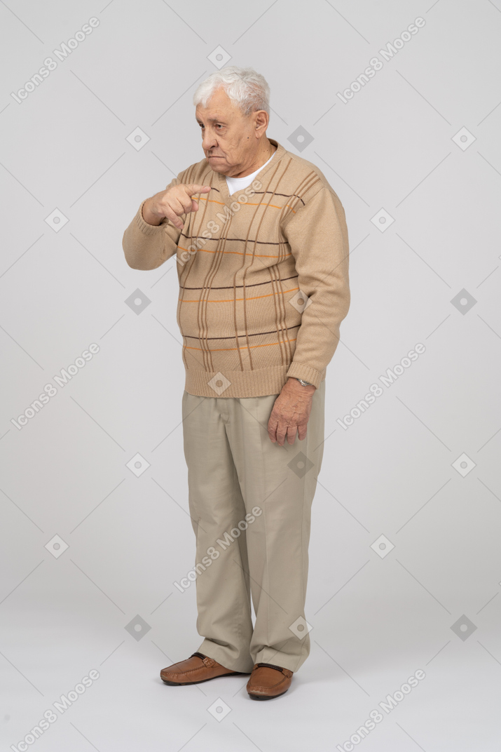 Vista frontal de um velho em roupas casuais apontando com o dedo