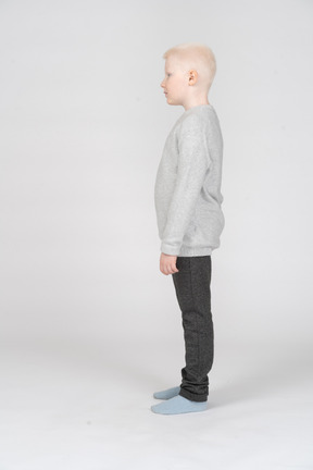 Side view of a kid boy standing still and looking aside