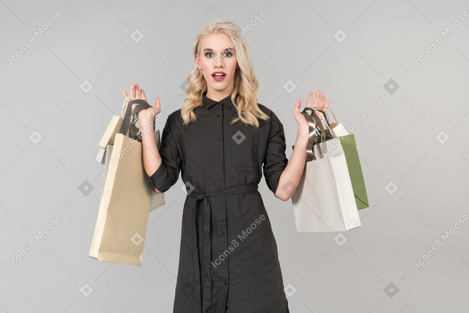 Une belle jeune personne aux cheveux blonds vêtue d'une robe noire tenant un tas de sacs à provisions à la main