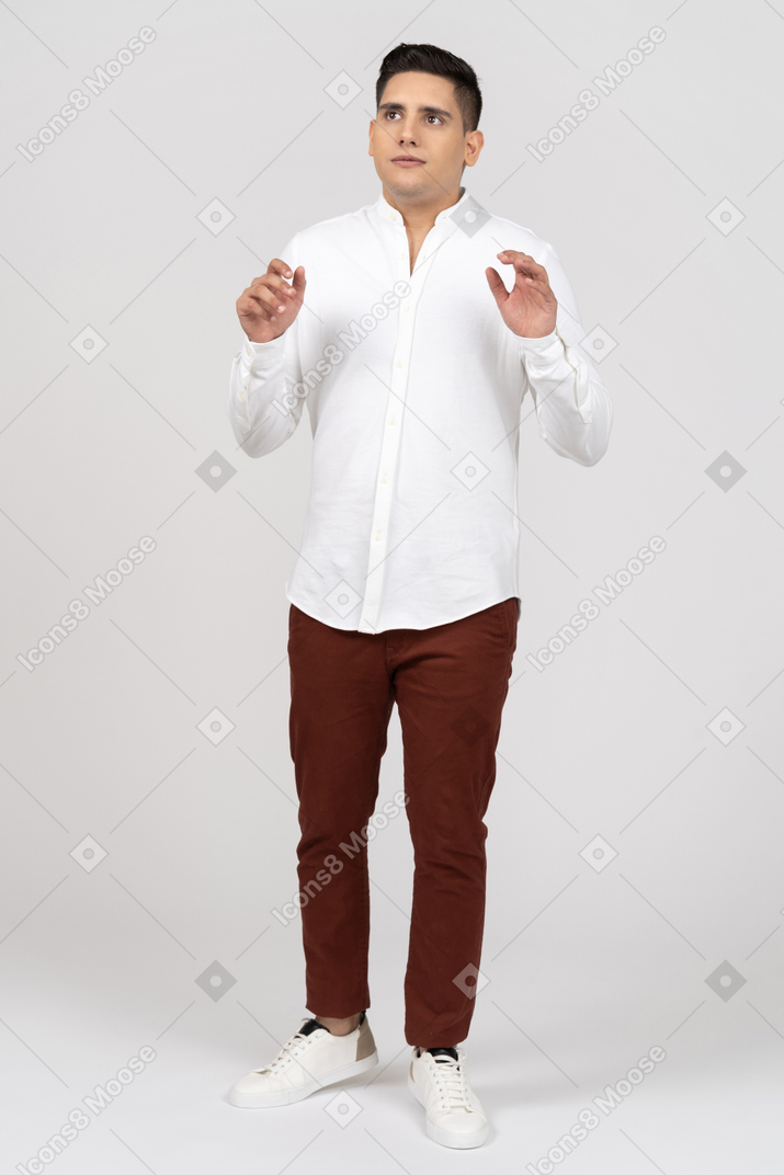 Front view of a young latino man looking aside and raising his hands uncertainly