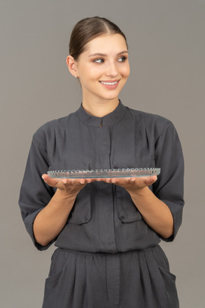 Front view of a young woman in a jumpsuit holding glass plate