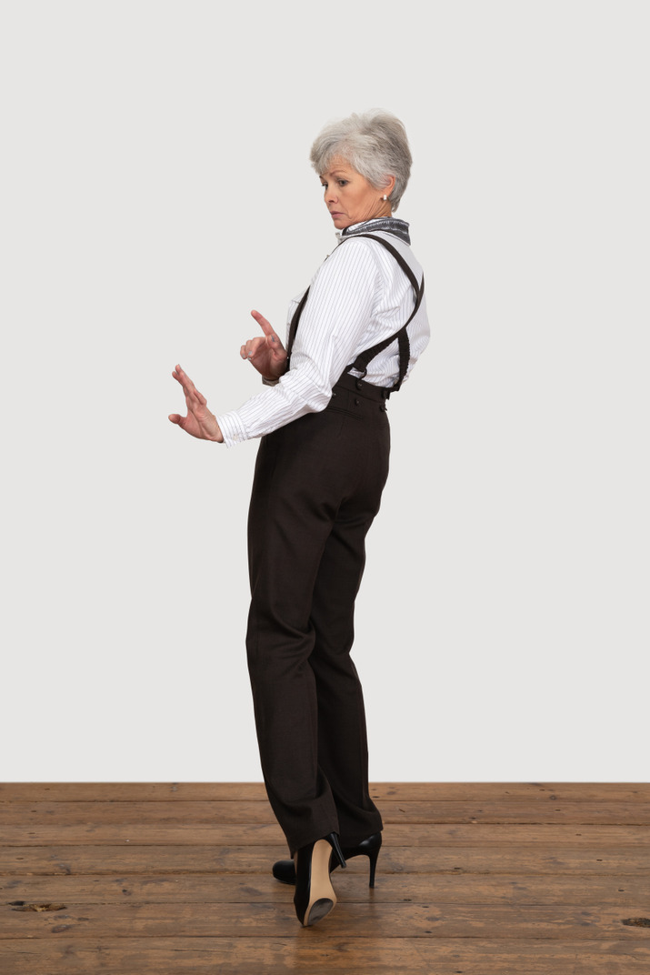 Three-quarter back view of a careful old lady outstretching her hands