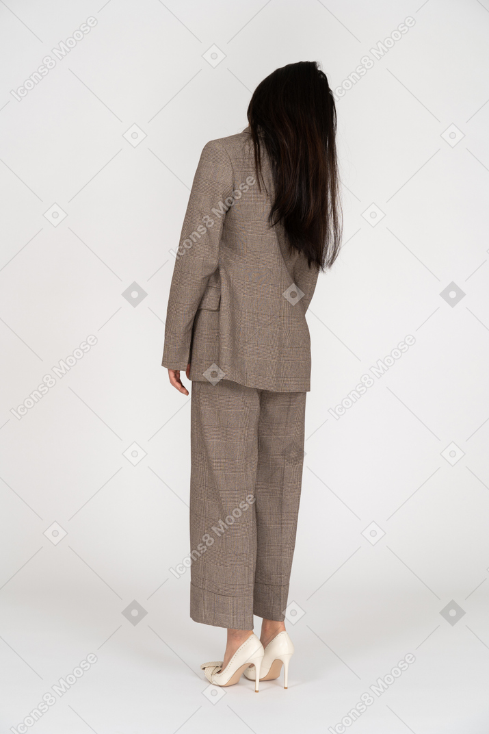 Vista posterior de tres cuartos de una joven en traje de negocios marrón inclinando la cabeza