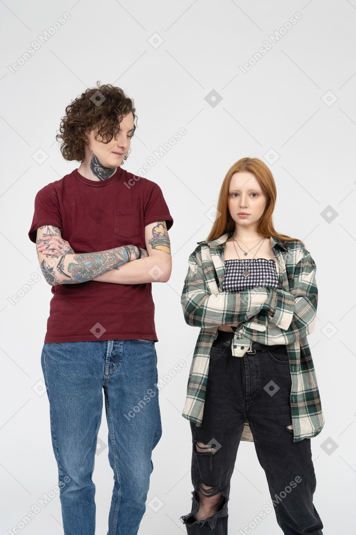 Teenage couple standing side by side with their arms crossed