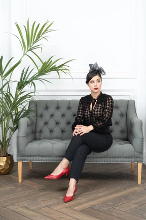 A woman sitting on top of a couch next to a potted plant