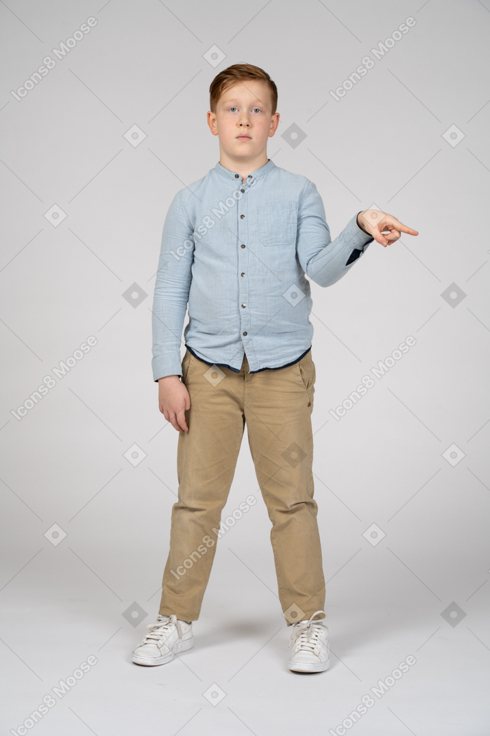 Front view of a boy pointing with finger and looking at camera